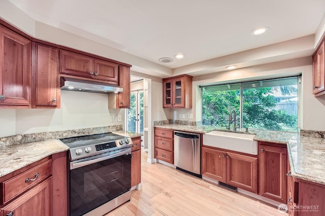 15831 Northup Way Unit 26, Bellevue, WA 98008 - kitchen with stainless steel appliances, under cabinet range hood, light wood-style floors, glass insert cabinets, and light stone countertops
