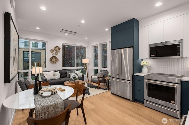 222B 10th Ave E, Seattle, WA 98102 - kitchen featuring stainless steel appliances, light wood finished floors, white cabinetry, recessed lighting, and light countertops