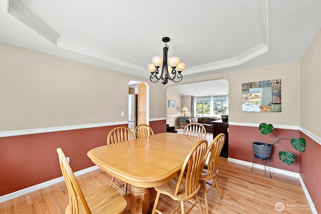 9321 339th St S Unit 5, Roy, WA 98580 - dining space with a tray ceiling, arched walkways, ornamental molding, a chandelier, and light wood-type flooring