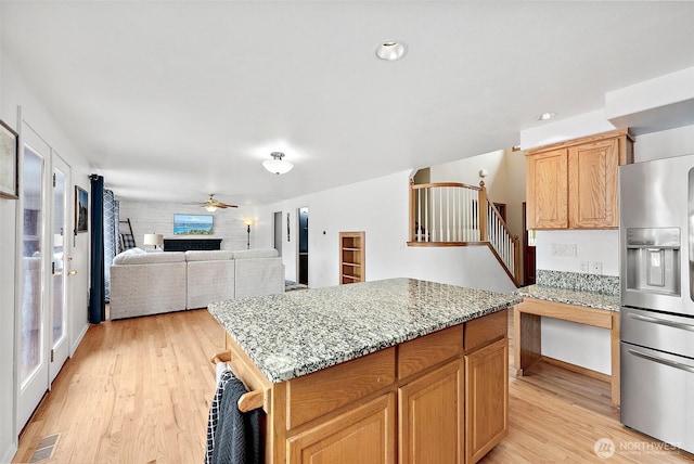 9321 339th St S Unit 5, Roy, WA 98580 - kitchen featuring stainless steel refrigerator with ice dispenser, light wood-type flooring, light stone countertops, a kitchen island, and ceiling fan