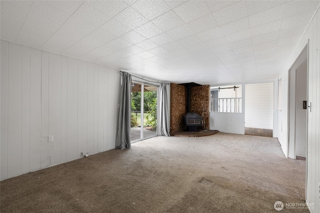 2220 91st St E, Tacoma, WA 98445 - unfurnished living room featuring a wood stove, carpet floors, and wood walls