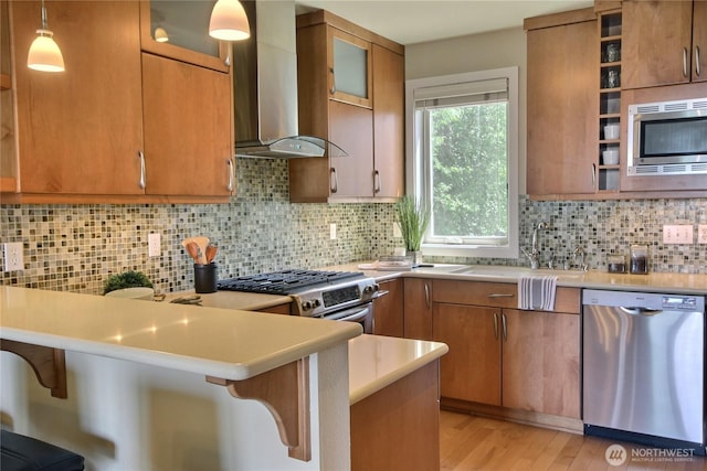 4411 Greenwood Ave N, Seattle, WA 98103 - kitchen with stainless steel appliances, wall chimney range hood, a peninsula, light countertops, and a breakfast bar