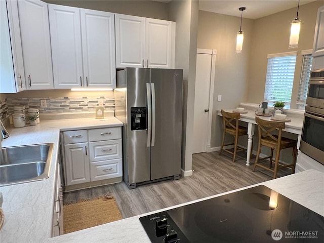 91 N Chandler Ct Unit D, Port Ludlow, WA 98365 - kitchen featuring stainless steel fridge, black electric stovetop, light wood-style flooring, and white cabinets