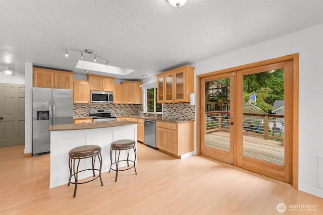 400 Sudden Valley Dr, Bellingham, WA 98229 - kitchen with stainless steel appliances, tasteful backsplash, light wood-style flooring, a kitchen island, and glass insert cabinets