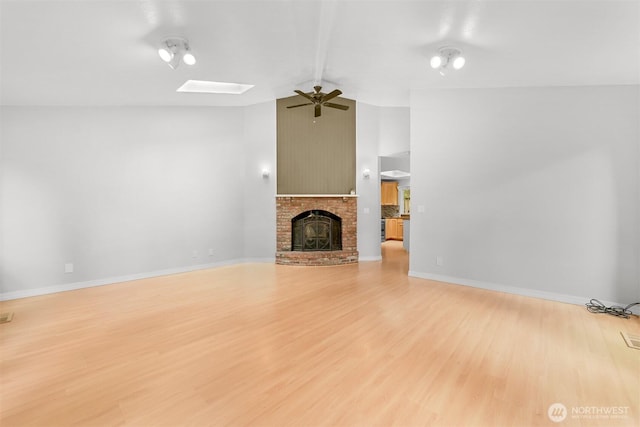 400 Sudden Valley Dr, Bellingham, WA 98229 - unfurnished living room with lofted ceiling, a ceiling fan, light wood-type flooring, a skylight, and a fireplace