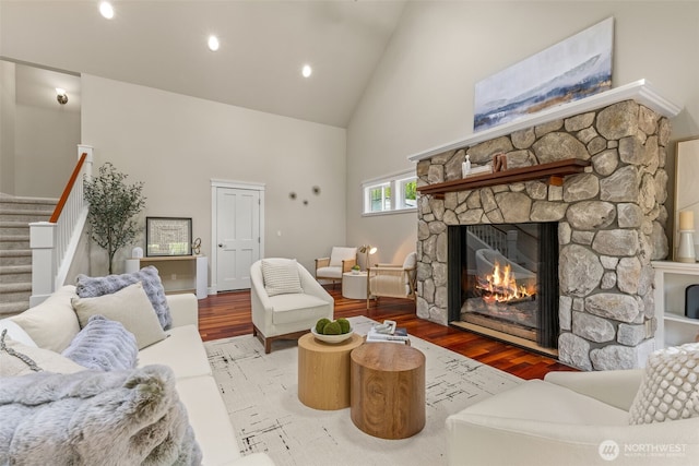 11028 E Riverside Dr, Bothell, WA 98011 - living room featuring high vaulted ceiling, a stone fireplace, wood finished floors, stairs, and recessed lighting