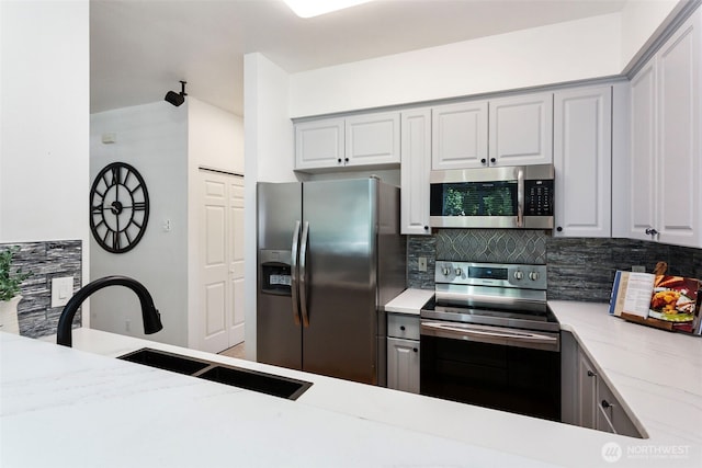 13000 Admiralty Way # D303, Everett, WA 98204 - kitchen featuring appliances with stainless steel finishes, decorative backsplash, light stone countertops, and gray cabinets