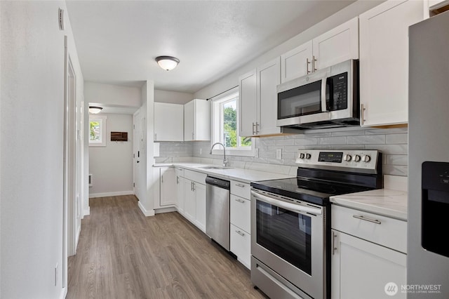8471 Golden Valley Dr, Maple Falls, WA 98266 - kitchen featuring stainless steel appliances, decorative backsplash, white cabinets, light wood-type flooring, and light stone countertops