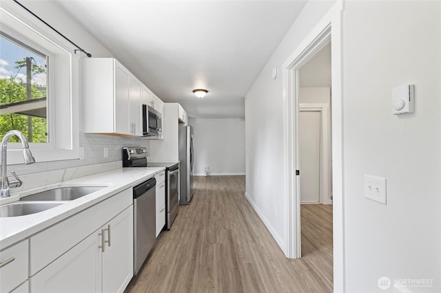 8471 Golden Valley Dr, Maple Falls, WA 98266 - kitchen with stainless steel appliances, white cabinets, light countertops, light wood-style floors, and tasteful backsplash