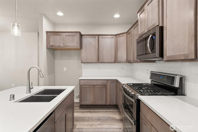 2883 74th Ln SW Unit Lot105, Tumwater, WA 98512 - kitchen featuring stainless steel appliances, light wood-style flooring, tasteful backsplash, hanging light fixtures, and light countertops