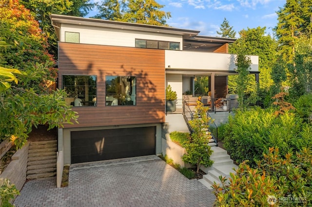 7826 115th Pl NE, Kirkland, WA 98033 - contemporary home featuring a garage, stairs, decorative driveway, a balcony, and stucco siding