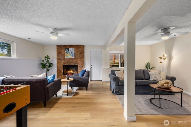 2012 SE 18th Ct, Renton, WA 98055 - living area featuring a ceiling fan, a textured ceiling, healthy amount of natural light, light wood-type flooring, and a brick fireplace
