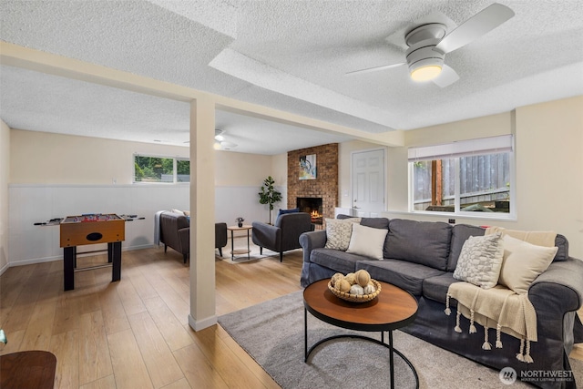 2012 SE 18th Ct, Renton, WA 98055 - living area with a ceiling fan, a textured ceiling, a brick fireplace, and light wood-style floors
