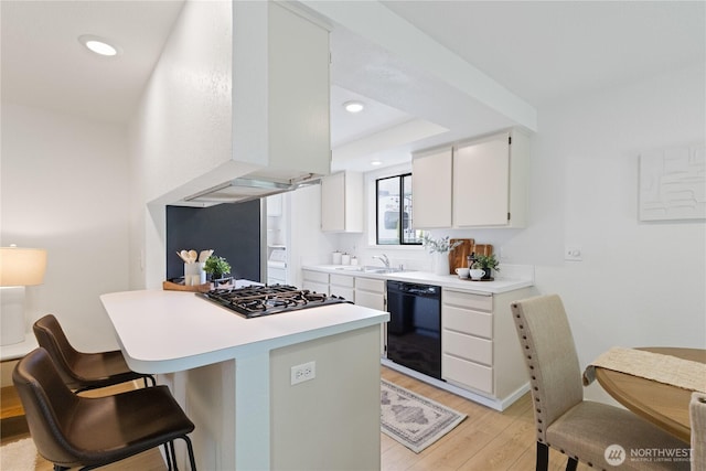 1708 24th Ct, Anacortes, WA 98221 - kitchen with black appliances, light countertops, light wood-style floors, white cabinetry, and a breakfast bar