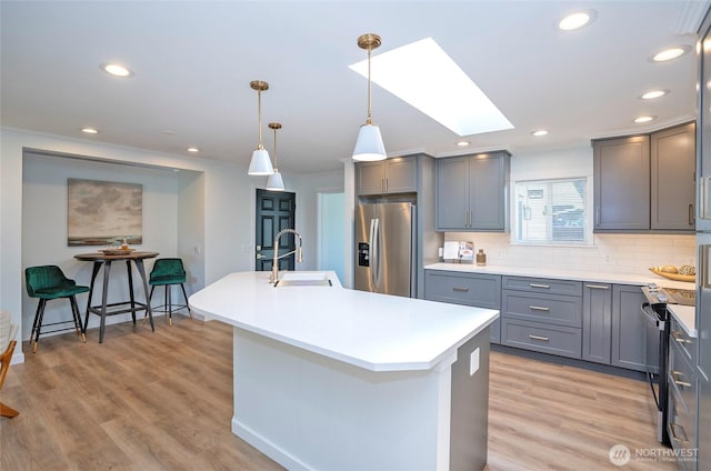 15512 Elm St E, Sumner, WA 98390 - kitchen featuring stainless steel fridge, gray cabinets, a skylight, ornamental molding, and an island with sink