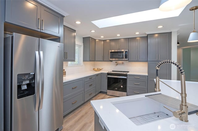 15512 Elm St E, Sumner, WA 98390 - kitchen featuring appliances with stainless steel finishes, gray cabinetry, a skylight, backsplash, and light wood-style flooring