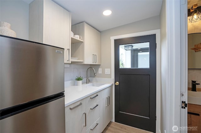 15512 Elm St E, Sumner, WA 98390 - kitchen featuring freestanding refrigerator, light countertops, backsplash, light wood finished floors, and recessed lighting
