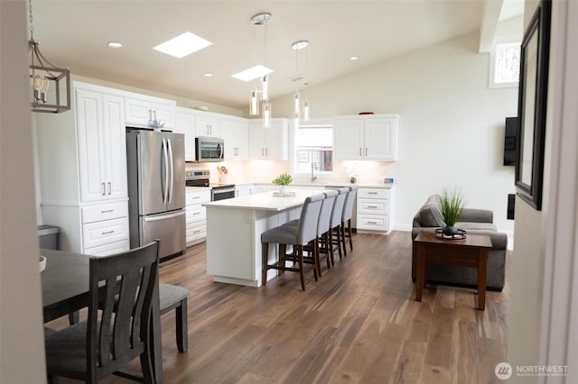 29813 L Ln, Ocean Park, WA 98640 - kitchen with appliances with stainless steel finishes, lofted ceiling, a breakfast bar area, white cabinets, and dark wood-style flooring