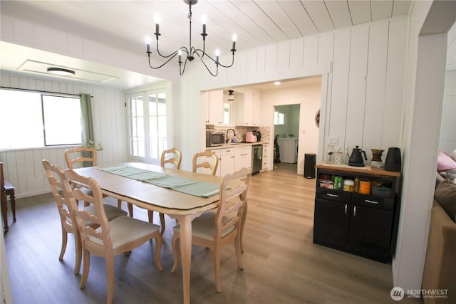 251 N 2nd St N, Buckley, WA 98321 - dining room featuring light wood-type flooring, a chandelier, washer / clothes dryer, and wooden walls