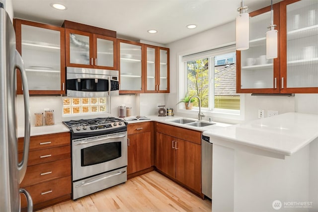 4220 Fremont Ave N Unit A, Seattle, WA 98103 - kitchen with stainless steel appliances, light wood-style flooring, brown cabinets, light countertops, and glass insert cabinets