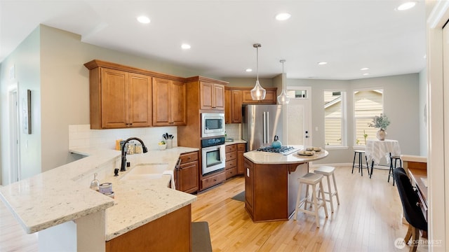 4597 Rutherford Cir SW, Port Orchard, WA 98367 - kitchen featuring stainless steel appliances, a breakfast bar, brown cabinetry, light wood-style flooring, and recessed lighting