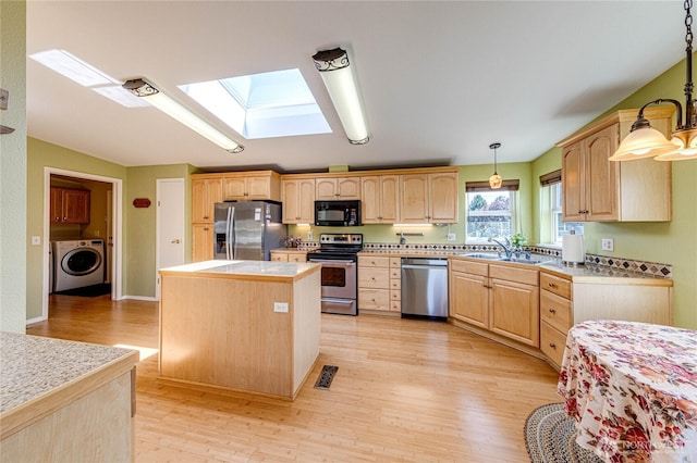 629 N 7th Ave, Sequim, WA 98382 - kitchen with appliances with stainless steel finishes, washer / dryer, light brown cabinets, a center island, and a skylight