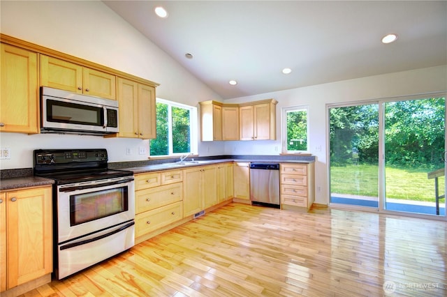 8391 Richmond Park Rd, Birch Bay, WA 98230 - kitchen with appliances with stainless steel finishes, light brown cabinetry, vaulted ceiling, dark countertops, and light wood-type flooring