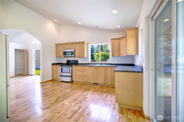 8391 Richmond Park Rd, Birch Bay, WA 98230 - kitchen with stainless steel appliances, arched walkways, light brown cabinets, light wood-style floors, and dark countertops