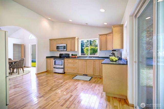 8391 Richmond Park Rd, Birch Bay, WA 98230 - kitchen with appliances with stainless steel finishes, arched walkways, dark countertops, light brown cabinetry, and light wood-style flooring