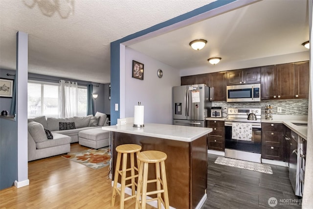 1938 66th Ave NE, Tacoma, WA 98422 - kitchen featuring appliances with stainless steel finishes, dark wood-type flooring, dark brown cabinetry, open floor plan, and a textured ceiling