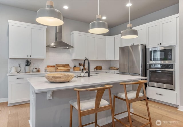 4561 Albatross St, Port Townsend, WA 98368 - kitchen featuring appliances with stainless steel finishes, wall chimney exhaust hood, a kitchen bar, tasteful backsplash, and recessed lighting