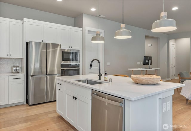 4561 Albatross St, Port Townsend, WA 98368 - kitchen with appliances with stainless steel finishes, an island with sink, white cabinets, light wood-type flooring, and backsplash