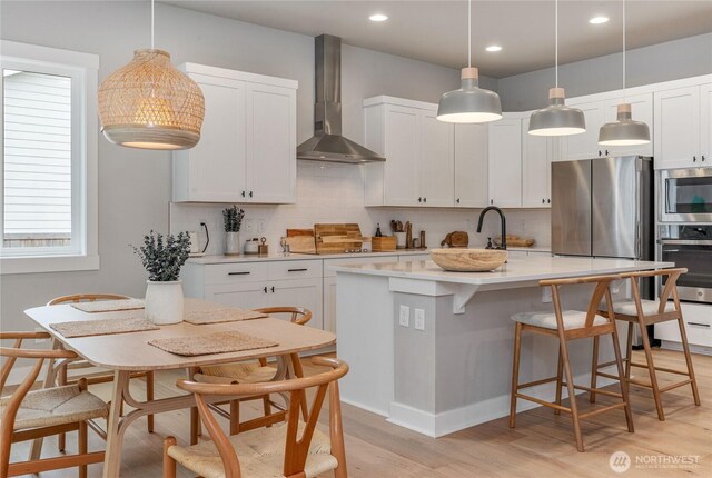 4561 Albatross St, Port Townsend, WA 98368 - kitchen with appliances with stainless steel finishes, wall chimney exhaust hood, light wood-style flooring, backsplash, and recessed lighting