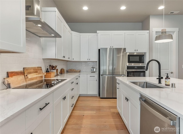 4561 Albatross St, Port Townsend, WA 98368 - kitchen featuring stainless steel appliances, wall chimney exhaust hood, white cabinetry, tasteful backsplash, and recessed lighting