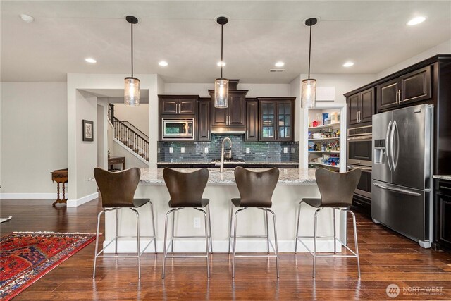 4410 Sentinel Ct, Gig Harbor, WA 98332 - kitchen with stainless steel appliances, tasteful backsplash, dark wood-style floors, dark brown cabinets, and a kitchen breakfast bar