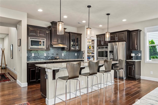 4410 Sentinel Ct, Gig Harbor, WA 98332 - kitchen featuring appliances with stainless steel finishes, dark wood-style floors, decorative backsplash, a center island with sink, and recessed lighting