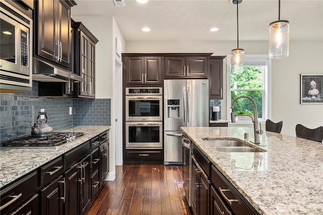 4410 Sentinel Ct, Gig Harbor, WA 98332 - kitchen with appliances with stainless steel finishes, dark wood-type flooring, light stone countertops, pendant lighting, and tasteful backsplash