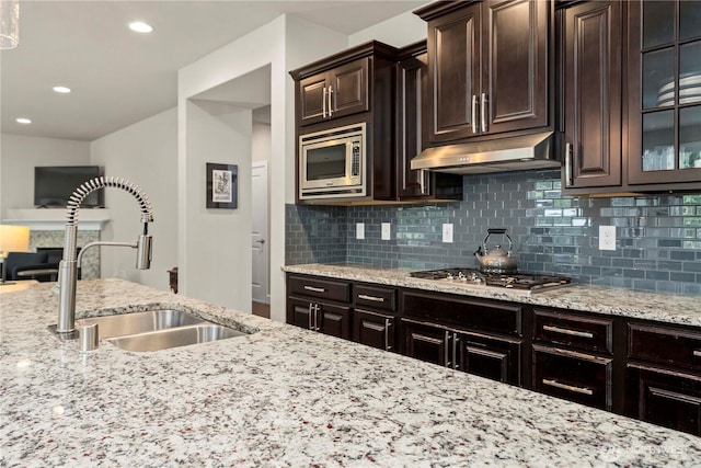 4410 Sentinel Ct, Gig Harbor, WA 98332 - kitchen featuring under cabinet range hood, appliances with stainless steel finishes, backsplash, light stone countertops, and glass insert cabinets