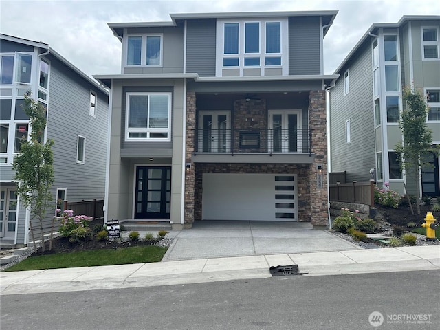 7559 S 130th Pl, Seattle, WA 98178 - view of front of house with french doors, stone siding, a balcony, concrete driveway, and a garage
