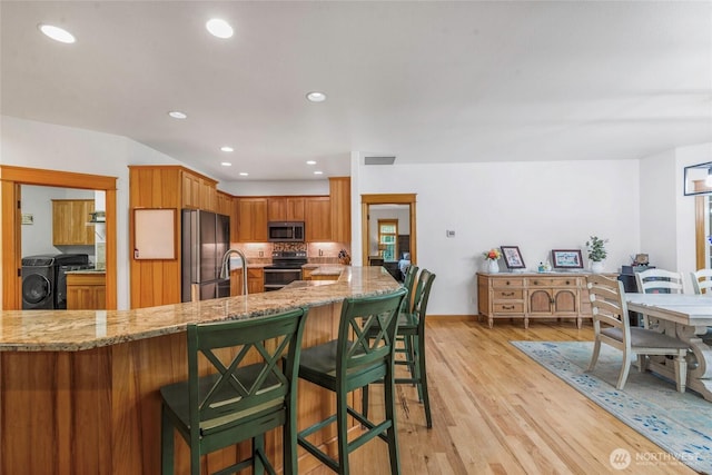 15949 159th Ln SE, Yelm, WA 98597 - kitchen featuring stainless steel appliances, light stone counters, light wood-style floors, recessed lighting, and a breakfast bar area