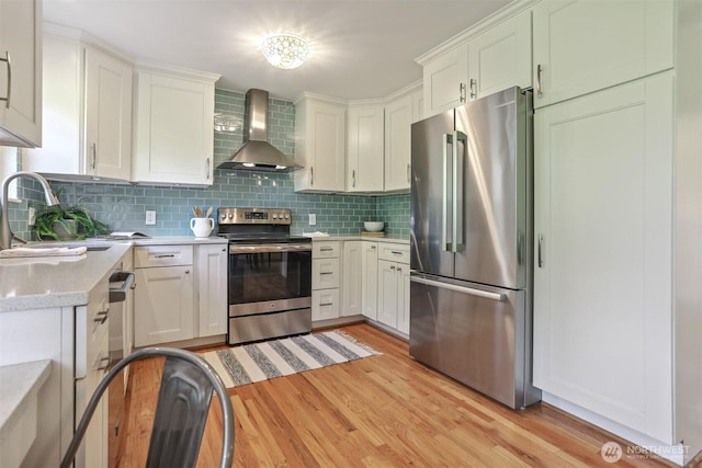 10718 12th Ave NW, Seattle, WA 98177 - kitchen featuring stainless steel appliances, wall chimney range hood, light wood finished floors, backsplash, and white cabinets