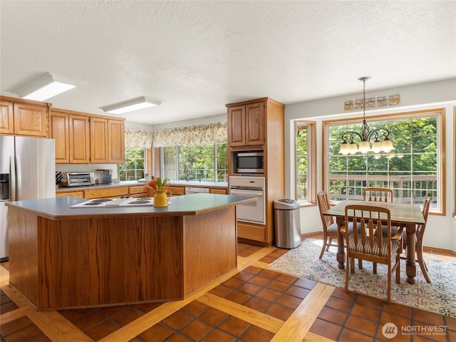 7842 Delphi Rd SW, Olympia, WA 98512 - kitchen featuring stainless steel appliances, a center island, a textured ceiling, a chandelier, and hanging light fixtures