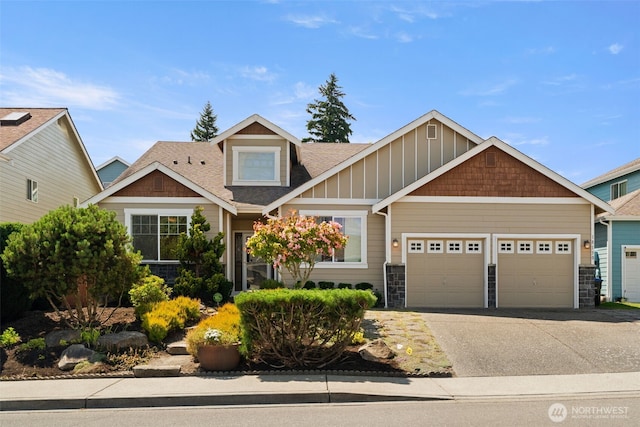 18130 Sunrise Ridge Ave NE, Poulsbo, WA 98370 - craftsman house featuring a garage, concrete driveway, roof with shingles, and stone siding