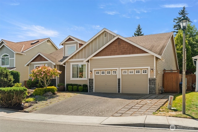 18130 Sunrise Ridge Ave NE, Poulsbo, WA 98370 - craftsman-style house with an attached garage, driveway, stone siding, a shingled roof, and board and batten siding