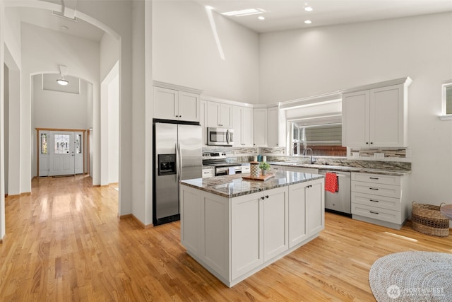 18130 Sunrise Ridge Ave NE, Poulsbo, WA 98370 - kitchen with a towering ceiling, appliances with stainless steel finishes, light stone countertops, a center island, and backsplash
