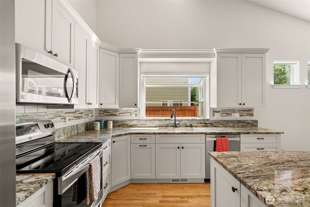 18130 Sunrise Ridge Ave NE, Poulsbo, WA 98370 - kitchen with appliances with stainless steel finishes, decorative backsplash, light wood finished floors, lofted ceiling, and light stone countertops