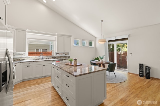18130 Sunrise Ridge Ave NE, Poulsbo, WA 98370 - kitchen featuring stainless steel fridge with ice dispenser, lofted ceiling, a kitchen island, light wood-style floors, and decorative backsplash