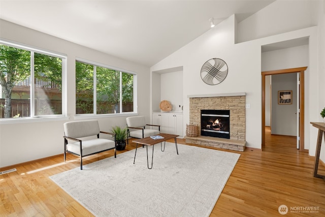 18130 Sunrise Ridge Ave NE, Poulsbo, WA 98370 - living area with light wood-type flooring, a stone fireplace, and high vaulted ceiling