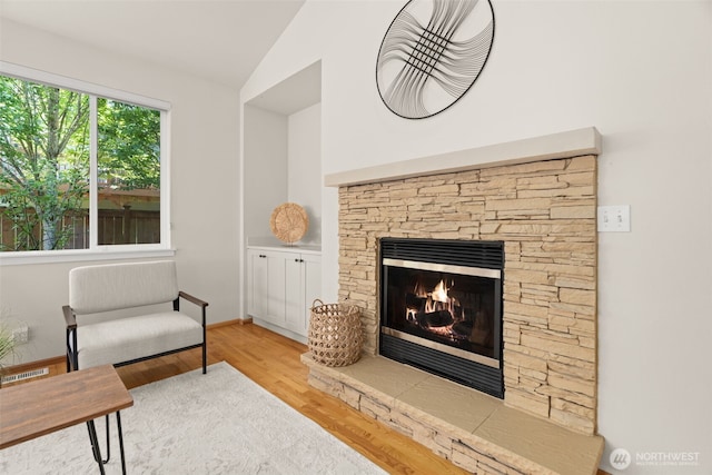 18130 Sunrise Ridge Ave NE, Poulsbo, WA 98370 - living room featuring vaulted ceiling, a stone fireplace, and wood finished floors