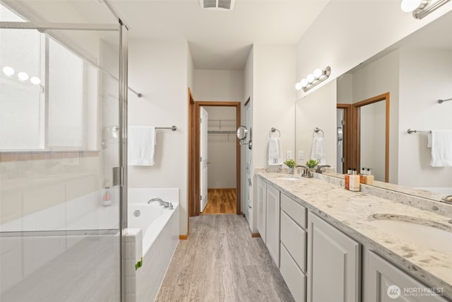 18130 Sunrise Ridge Ave NE, Poulsbo, WA 98370 - bathroom featuring double vanity, a stall shower, a bath, wood finished floors, and a spacious closet